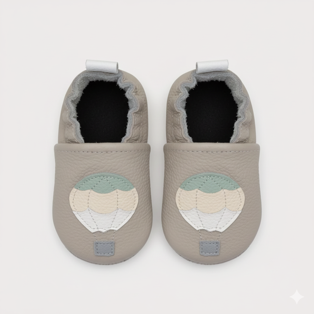 Pair of gray baby shoes with a decorative patch on a white background