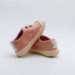 Pair of pink children's shoes with white soles on a light gray background