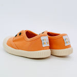 Orange children's sneakers with white soles on a light gray background