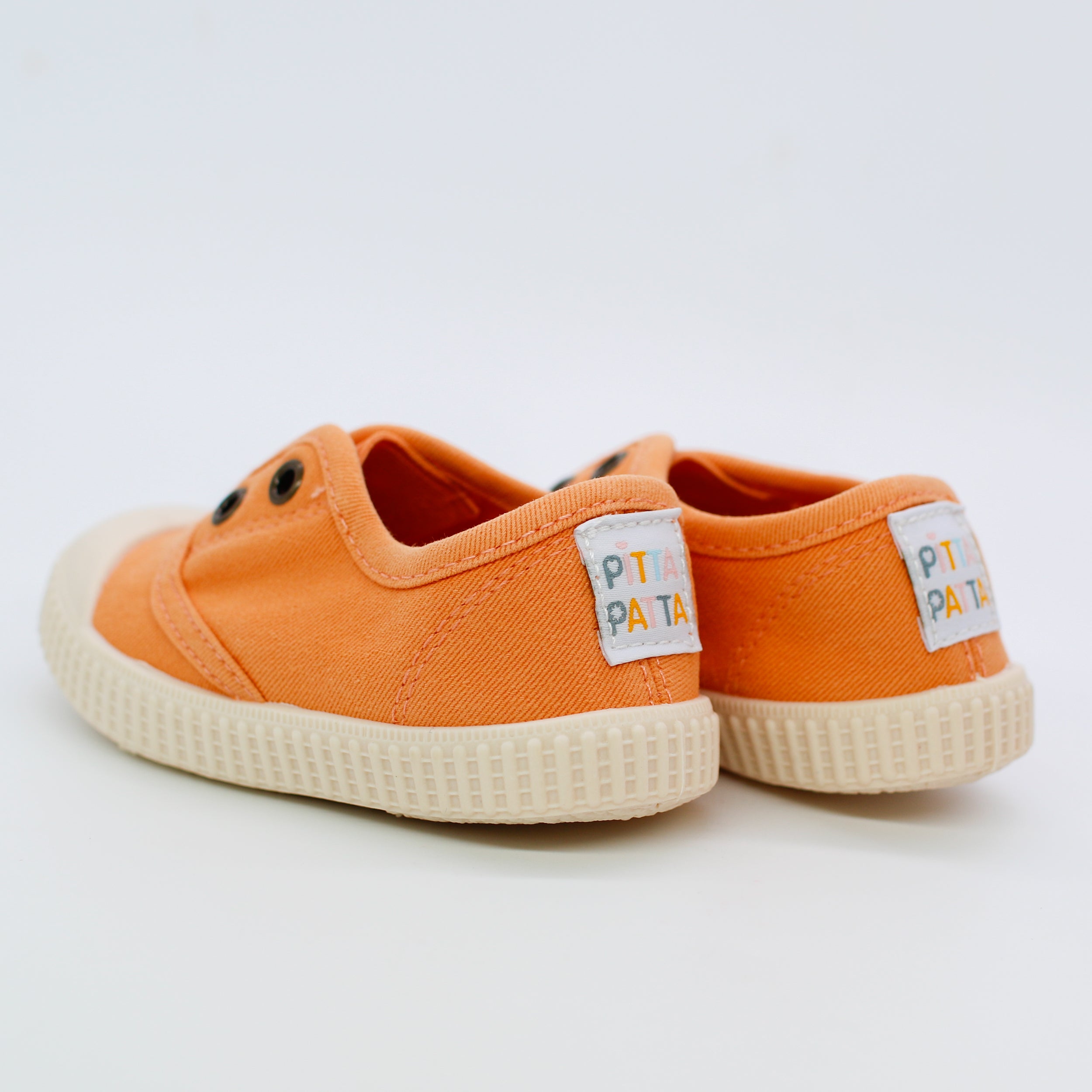 Orange children's sneakers with white soles on a light gray background