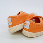 Pair of orange children's shoes with visible brand label on a light background