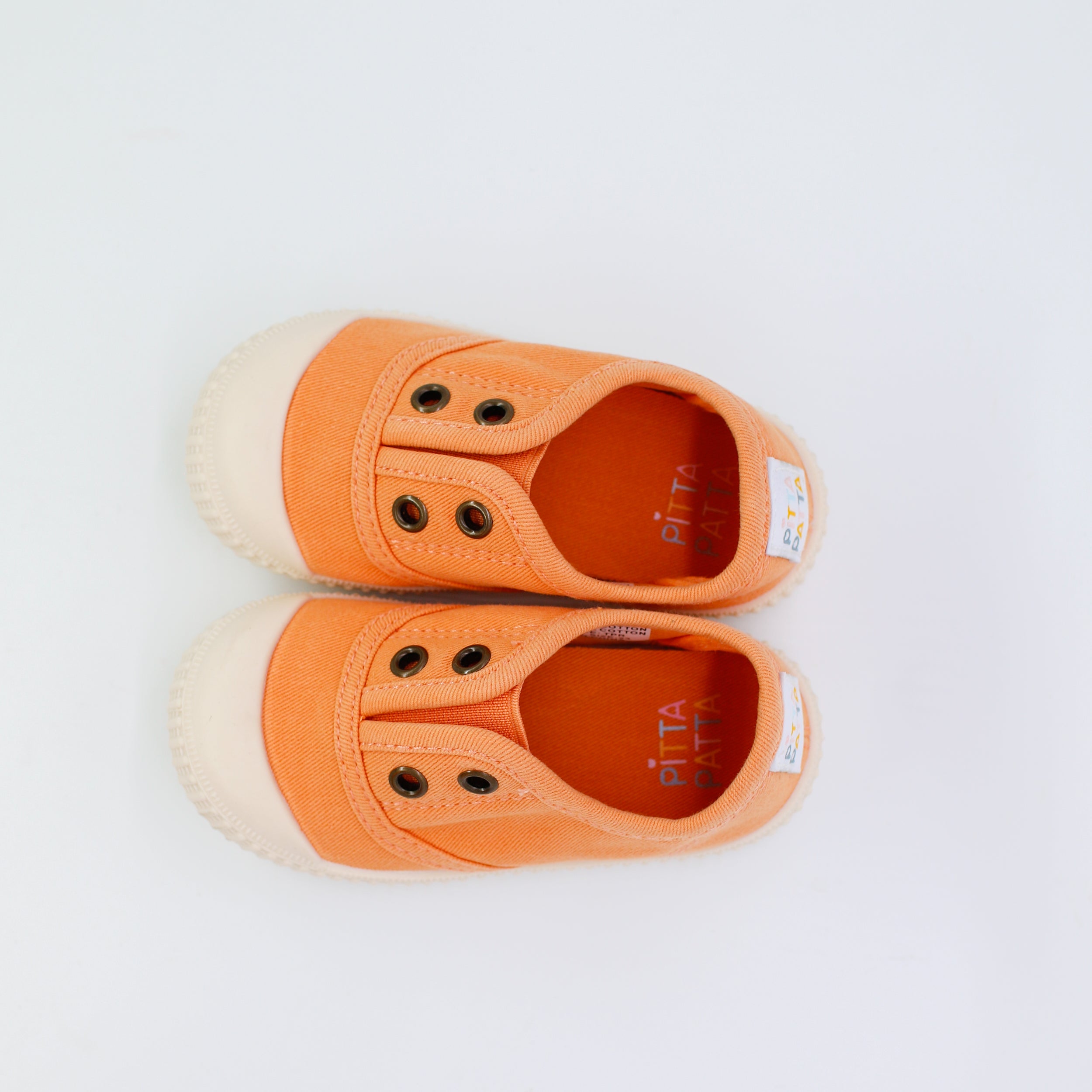 Pair of orange children's shoes on a white background