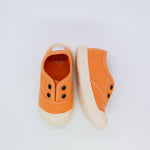 Pair of orange children's shoes with white soles on a light gray background