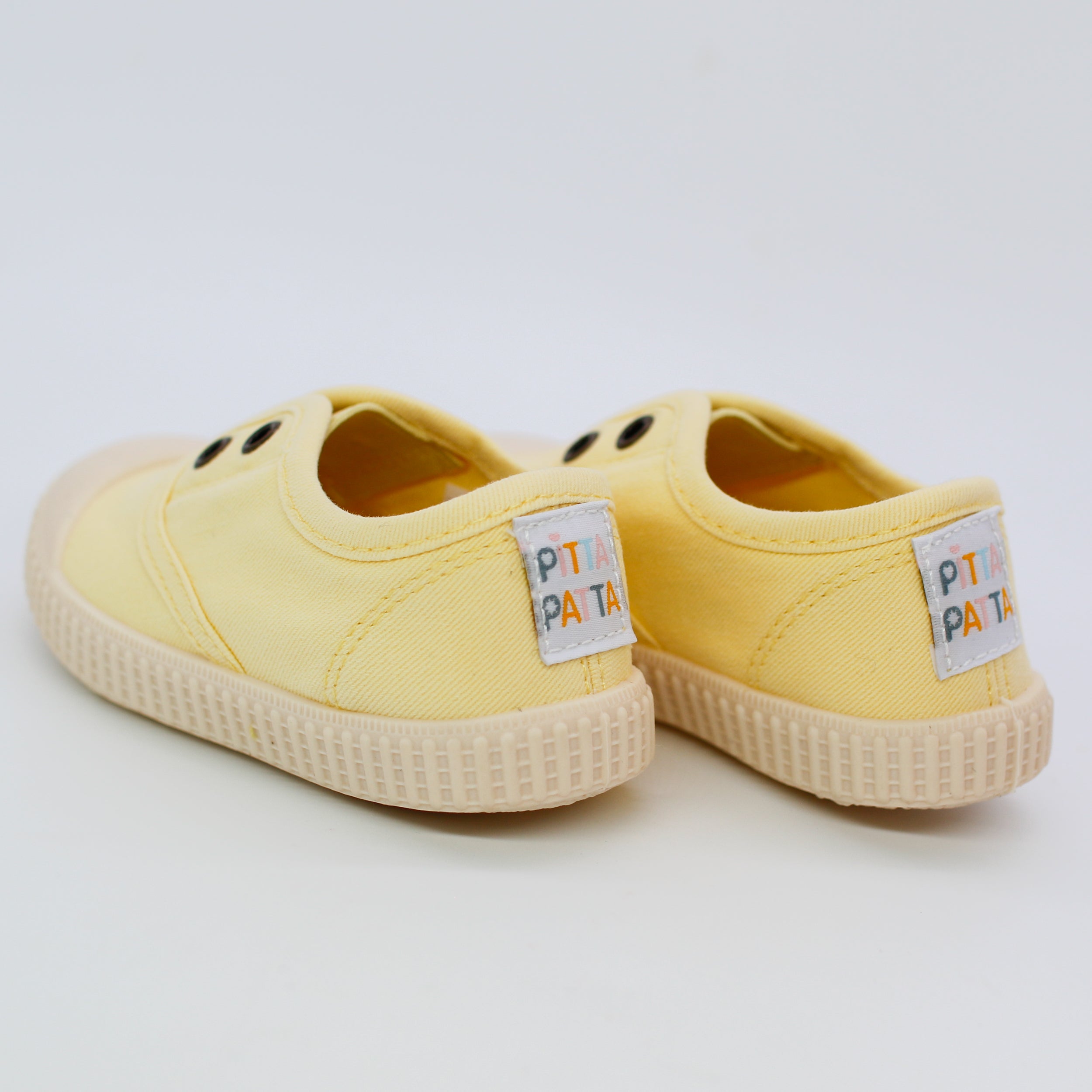 Pair of yellow children's shoes with 'Pipatata' labels on a white background