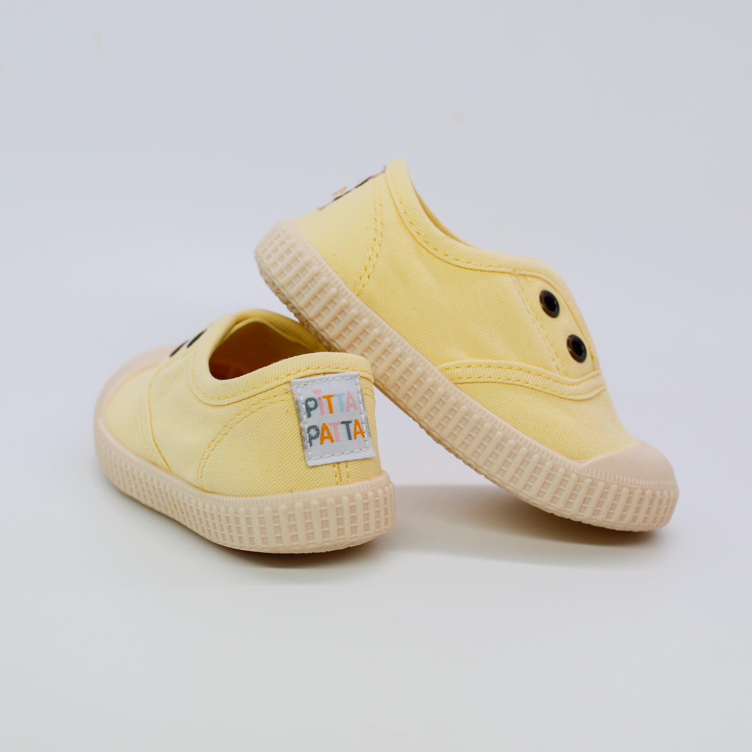 Pair of yellow children's sneakers with a visible brand label on a light gray background