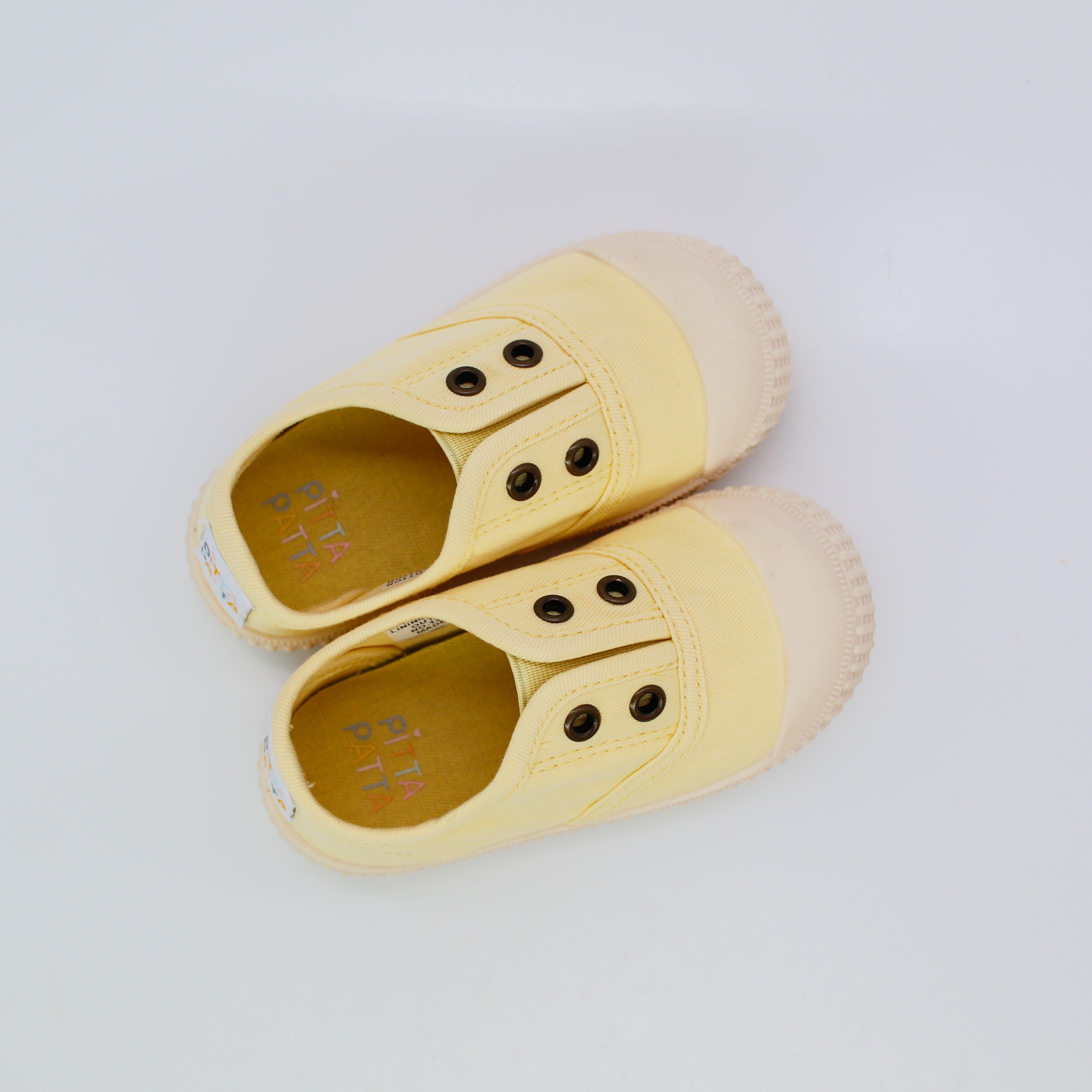Pair of yellow children's shoes with button details on a light gray background