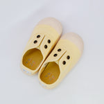 Pair of yellow slip-on shoes with button details on a white background