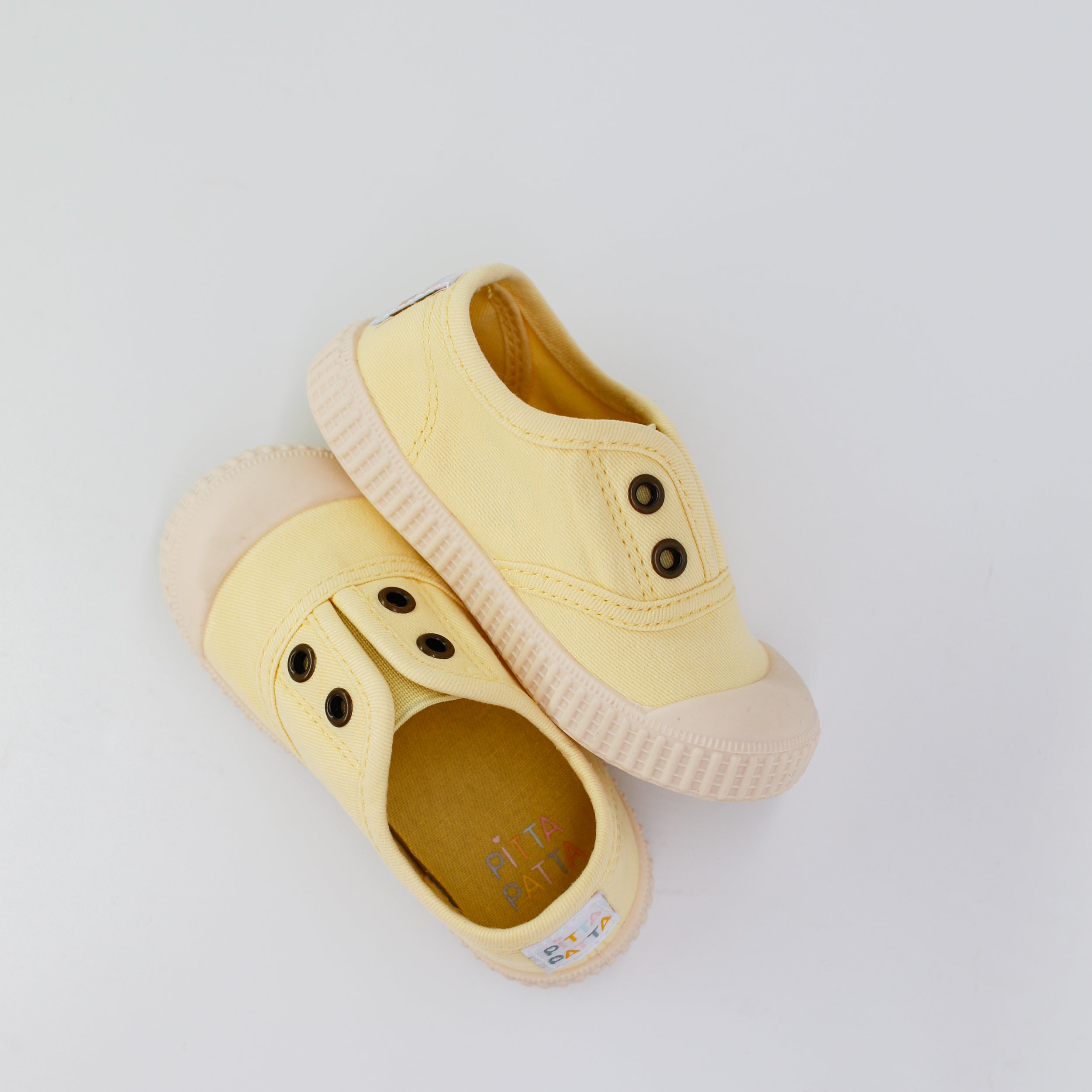 Pair of yellow children's shoes on a light gray background