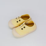Pair of yellow children's shoes on a light gray background