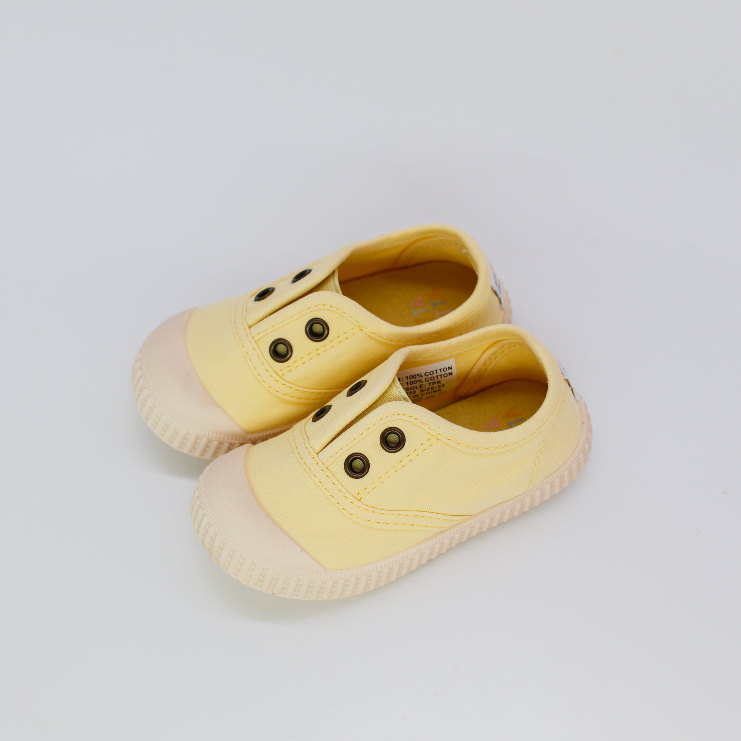 Pair of yellow children's shoes on a light gray background