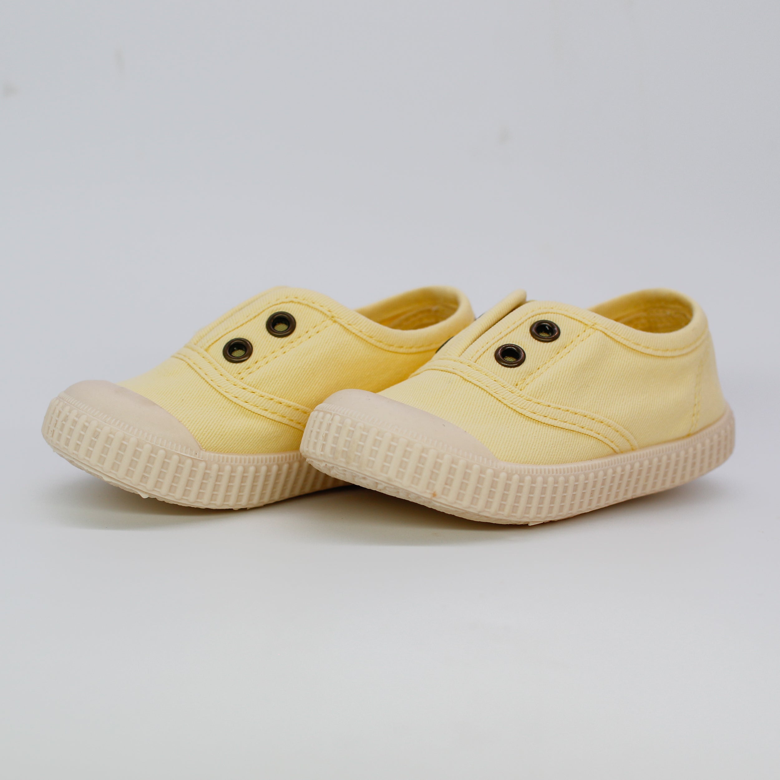 Pair of yellow children's shoes on a light gray background