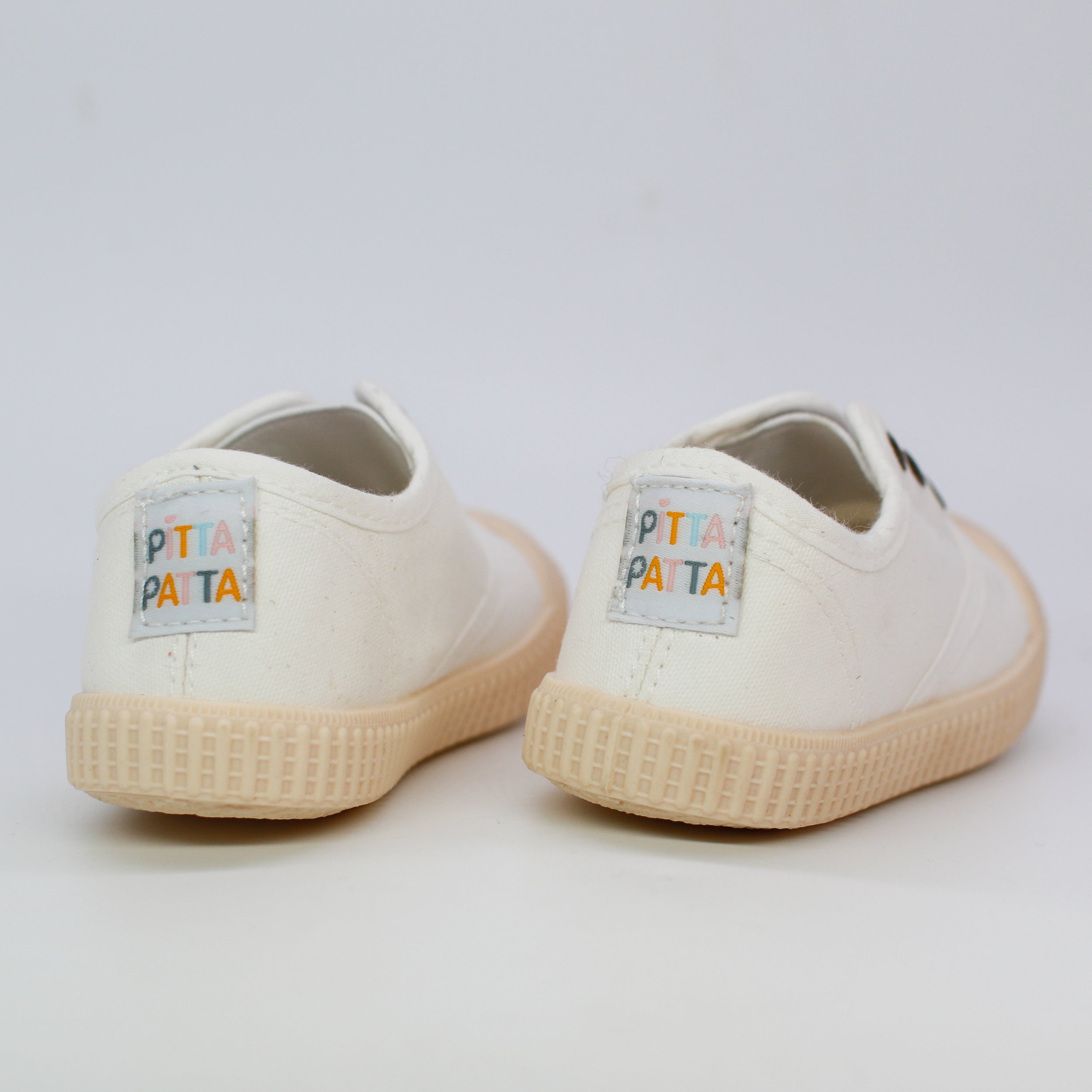 Pair of white sneakers with 'Pita Pata' branding on a light gray background