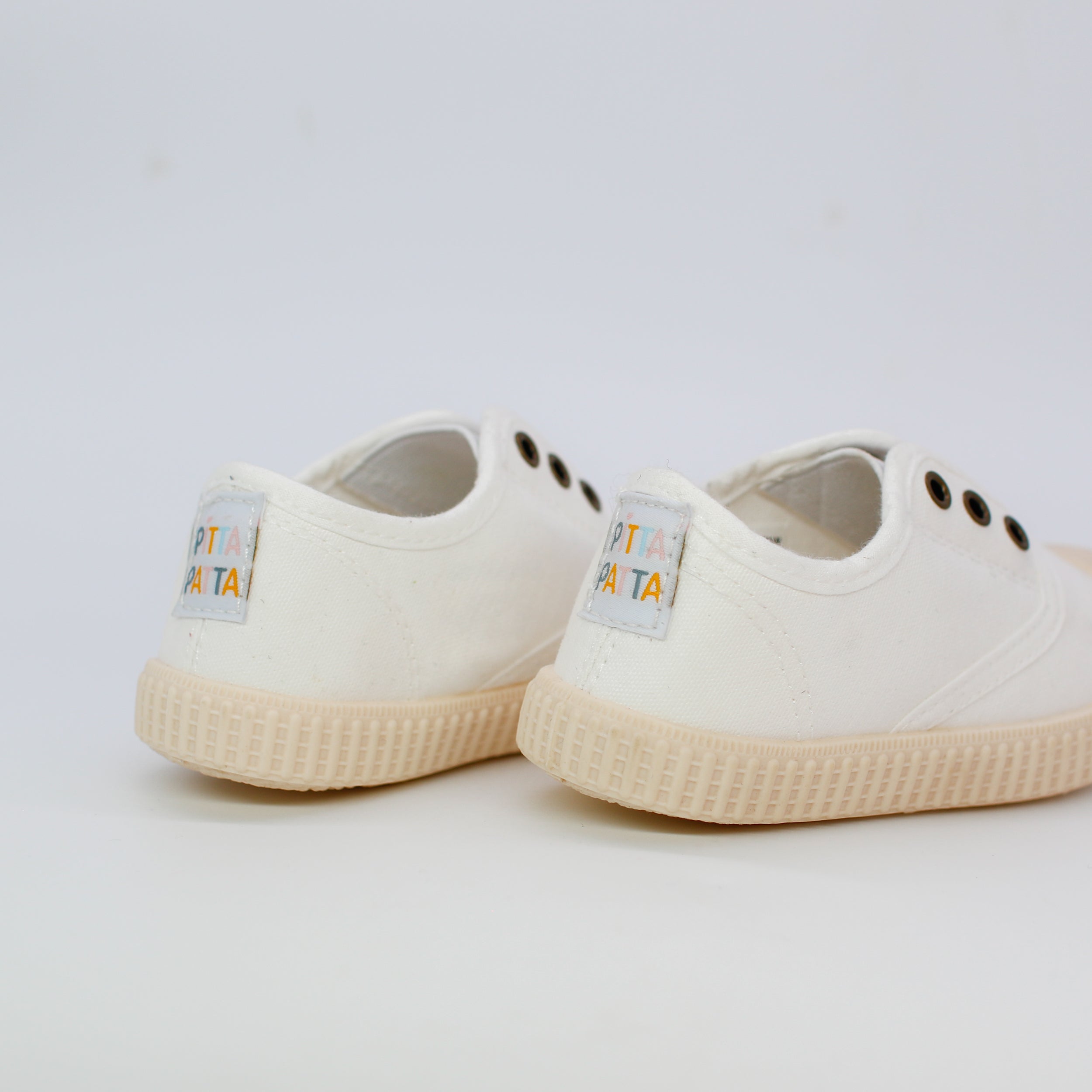 White sneakers with brand labels on a light gray background