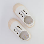 Pair of white children's shoes with beige soles on a light gray background