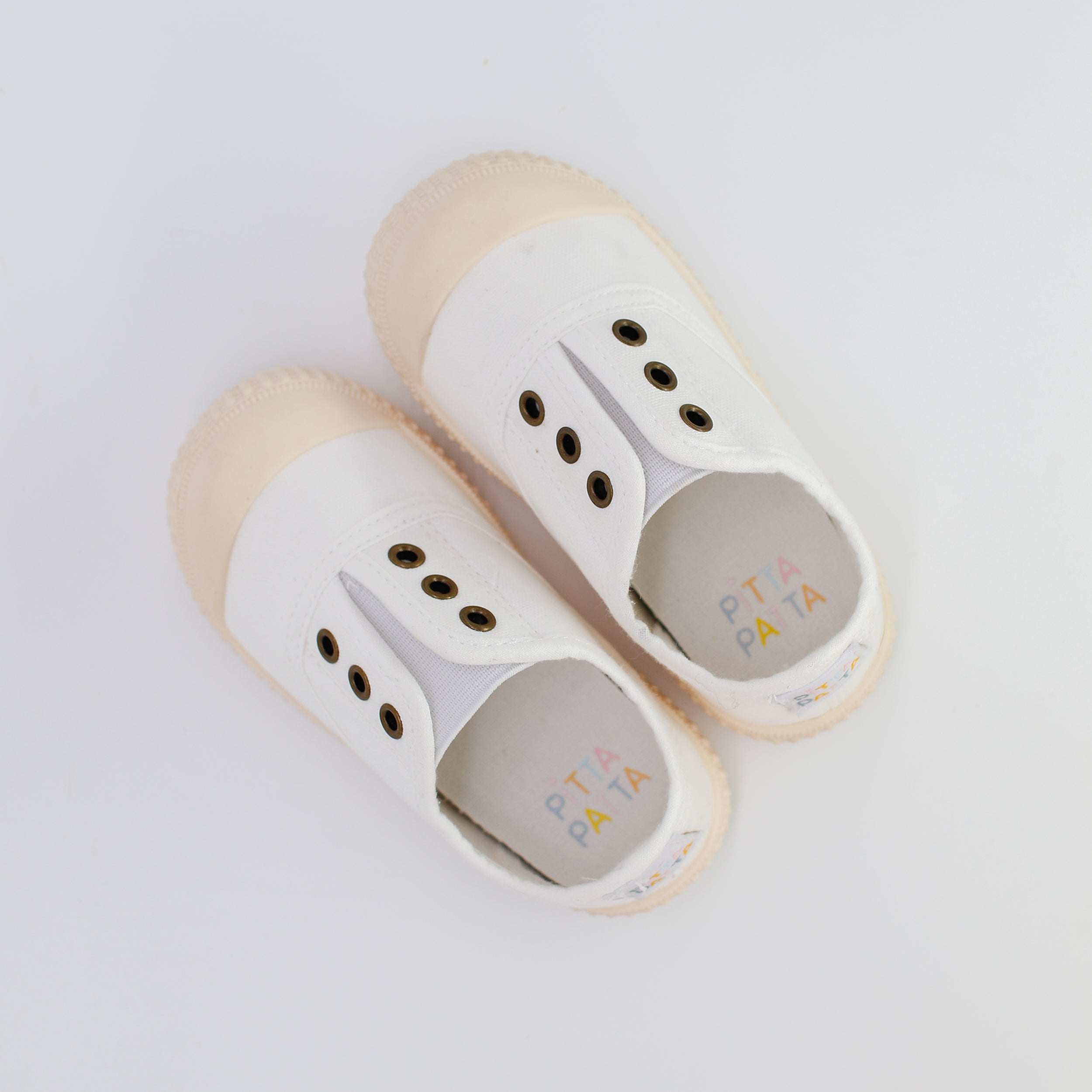 Pair of white slippers with beige soles on a light gray background
