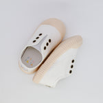 Pair of white sandals with beige soles on a light gray background