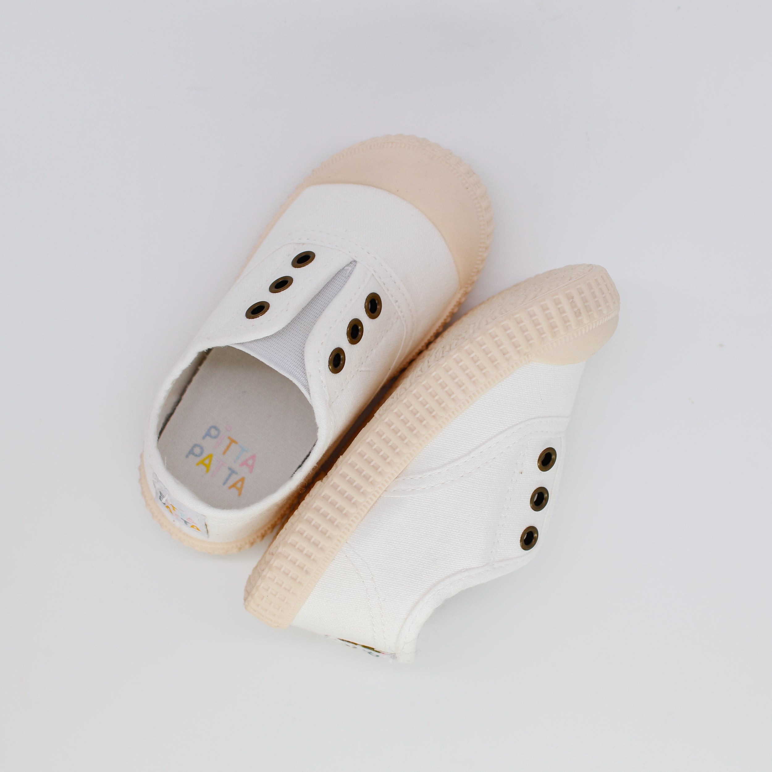 Pair of white sandals with beige soles on a light gray background