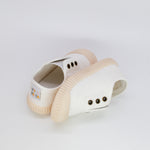 Pair of white clogs with beige soles on a light gray background