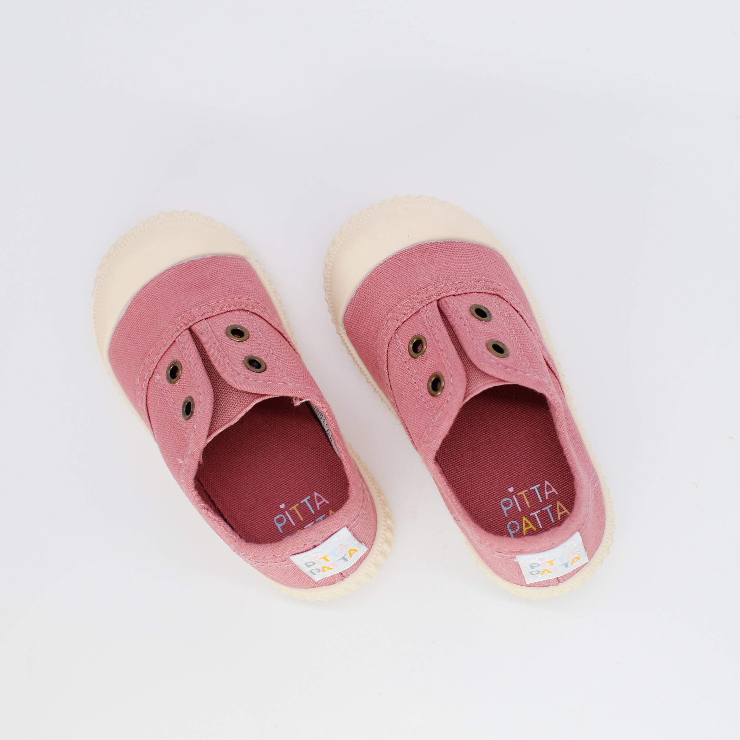 Pair of pink children's shoes with beige soles on a white background