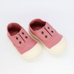 Pair of pink baby shoes with white soles on a light gray background