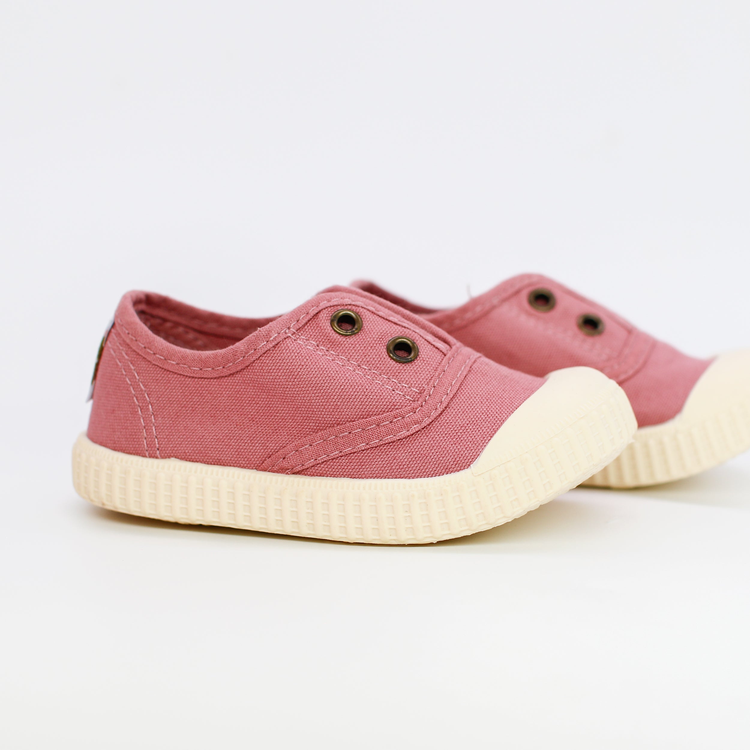 Pair of pink children's sneakers with white soles on a light background