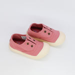 Pair of pink children's shoes with white soles on a light gray background