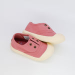 Pair of pink children's shoes with white soles on a light gray background