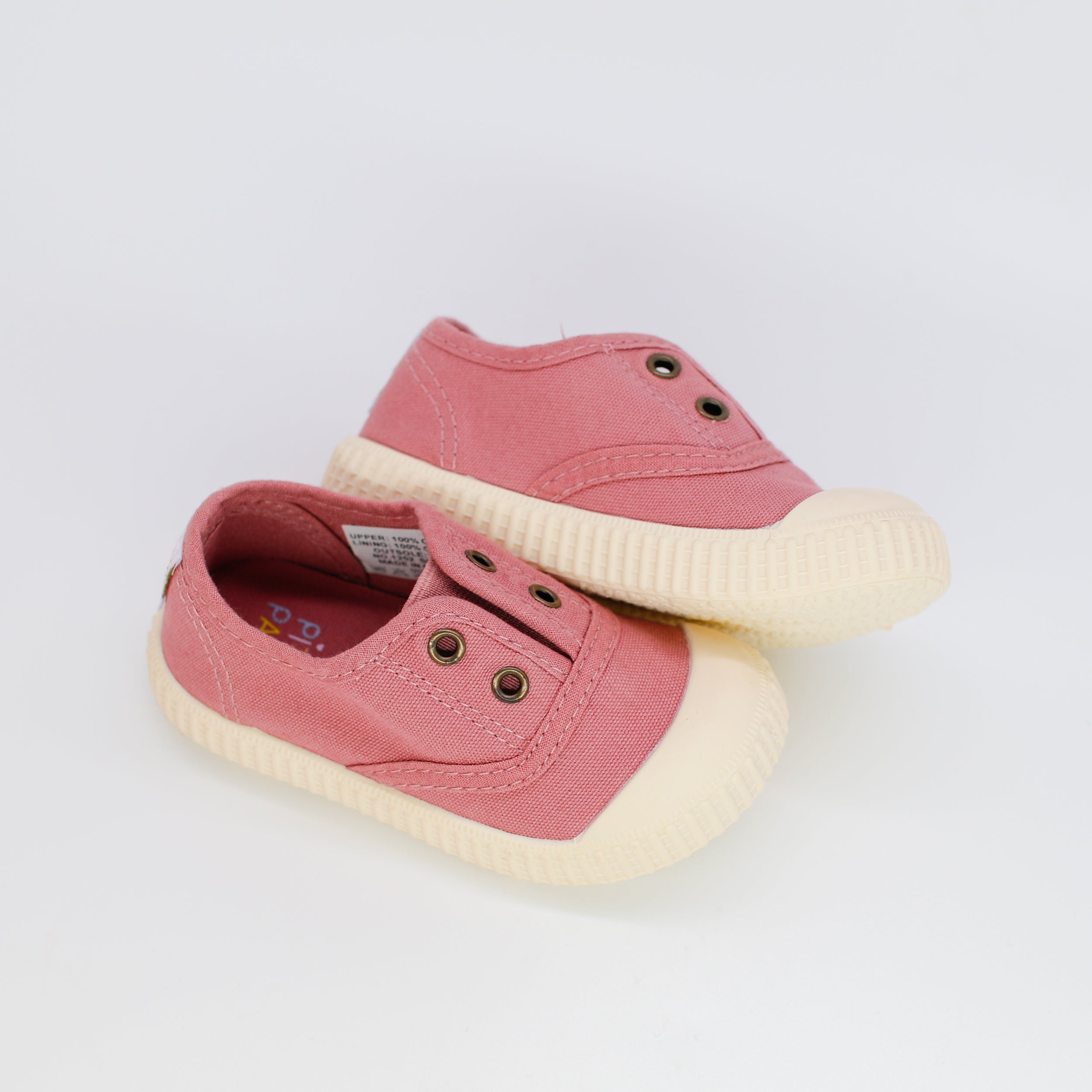Pair of pink children's shoes with white soles on a light gray background