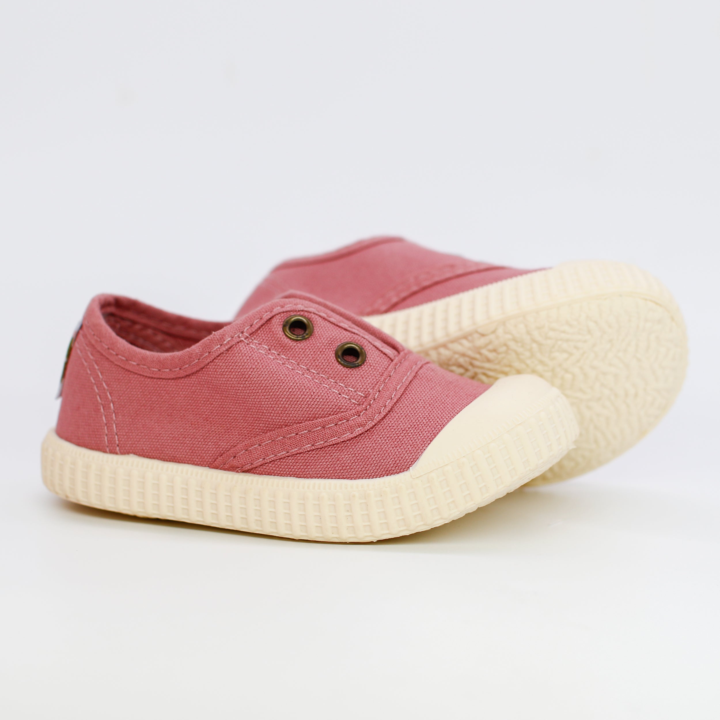 Pink children's shoes with white soles on a light gray background