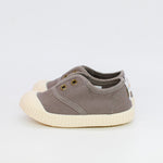 Pair of gray children's shoes with white soles on a light gray background