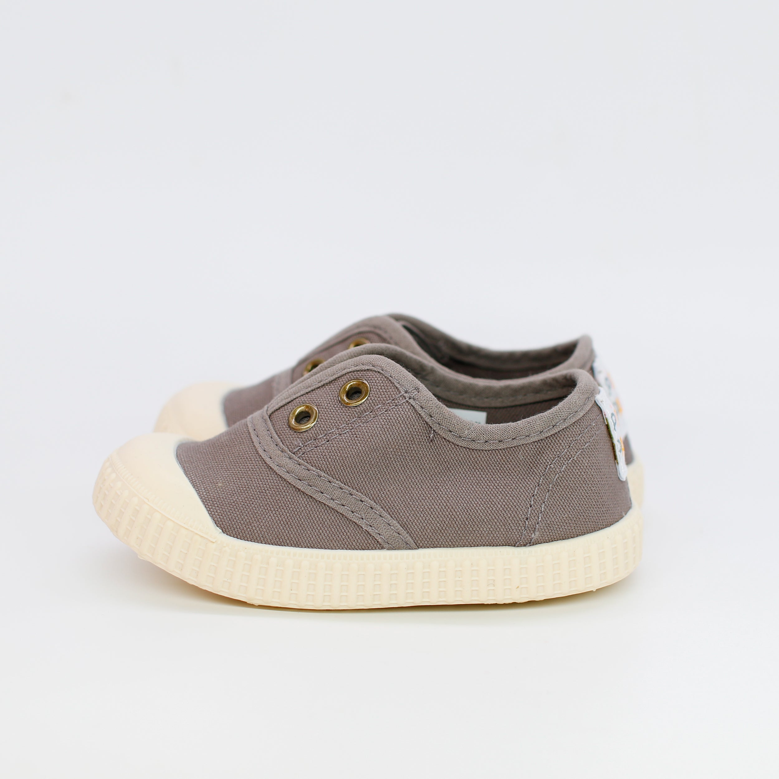 Pair of gray children's shoes with white soles on a light gray background