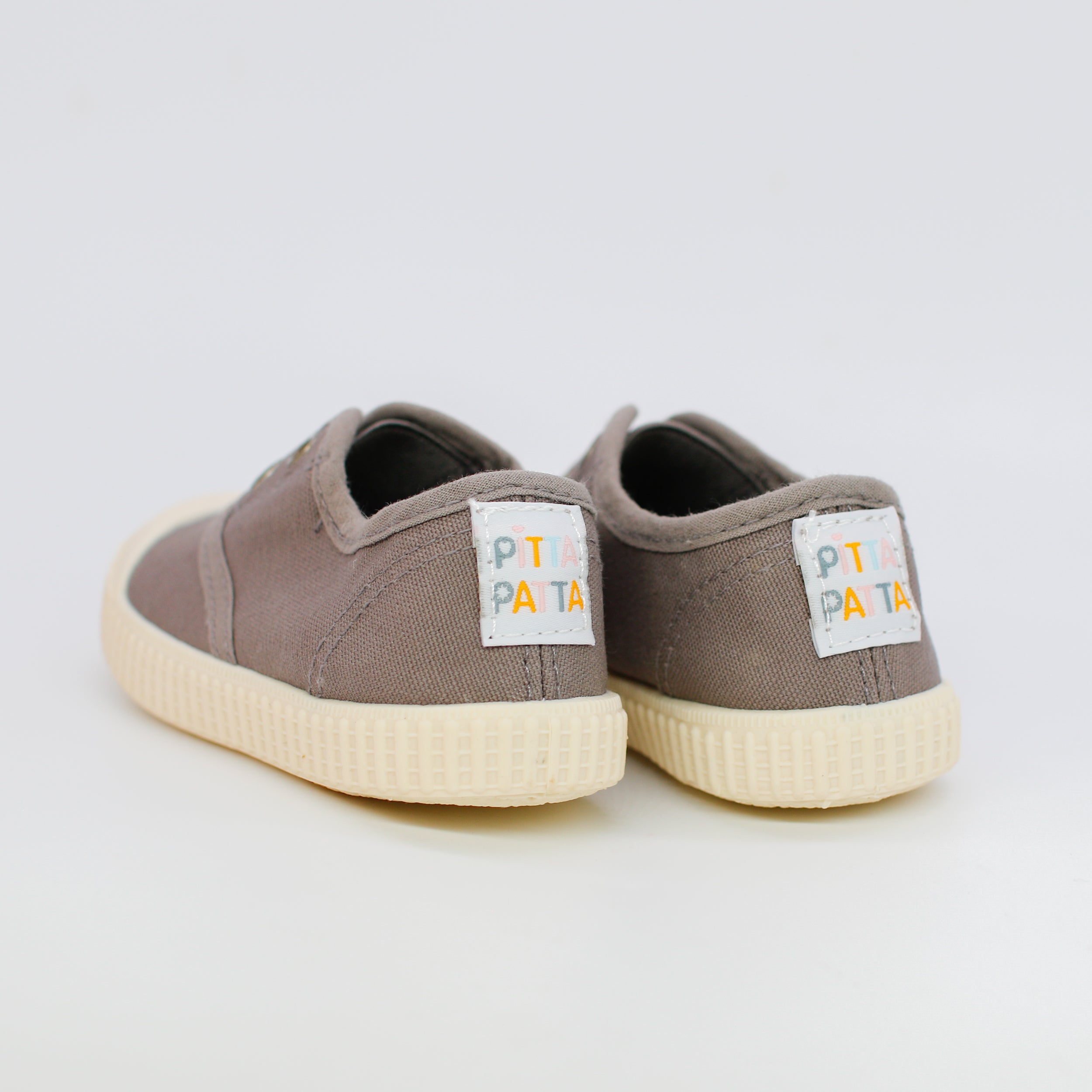Pair of brown children's sneakers with visible brand label on a light gray background