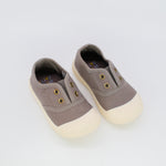 Pair of brown children's shoes with white soles on a light gray background