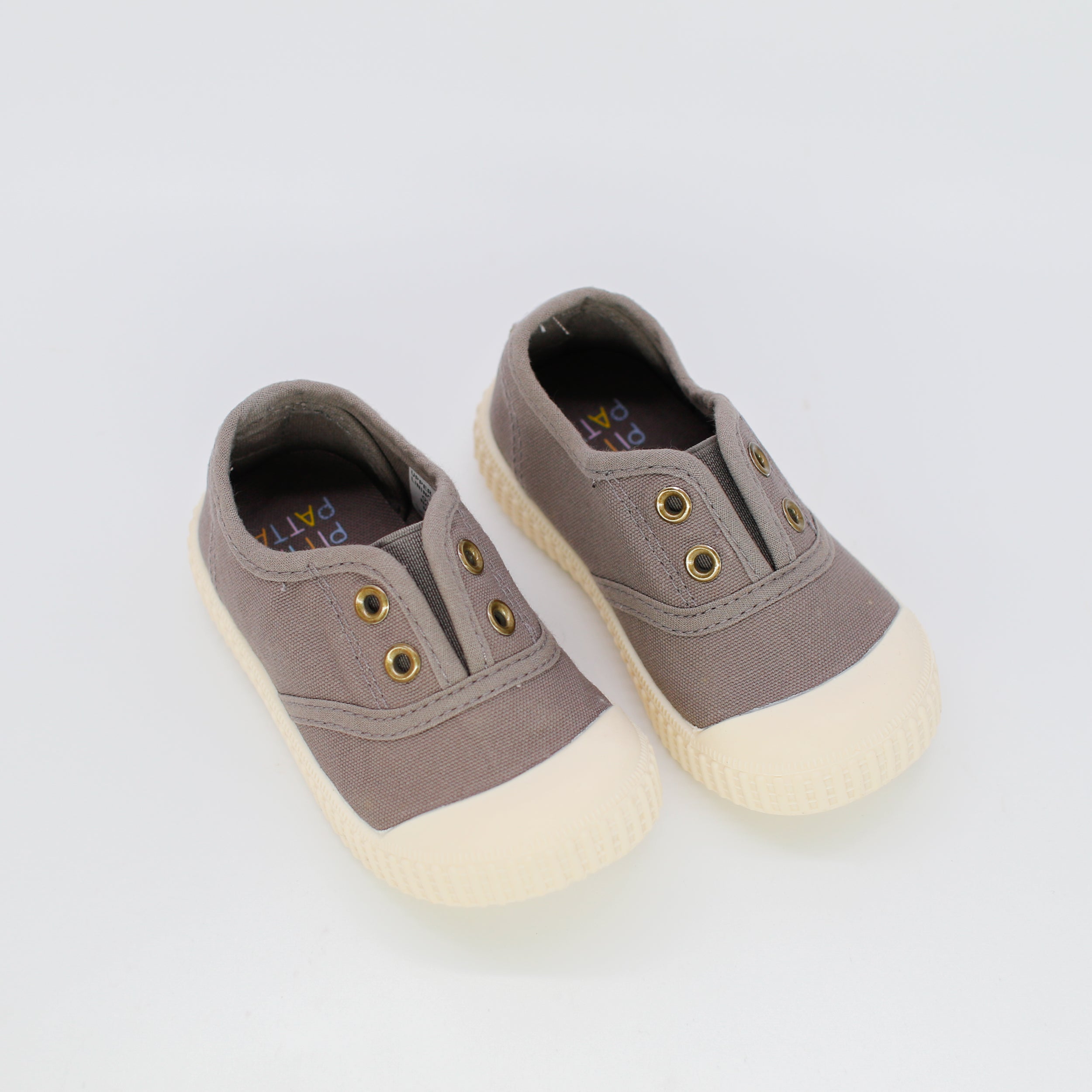 Pair of brown children's shoes with white soles on a light gray background