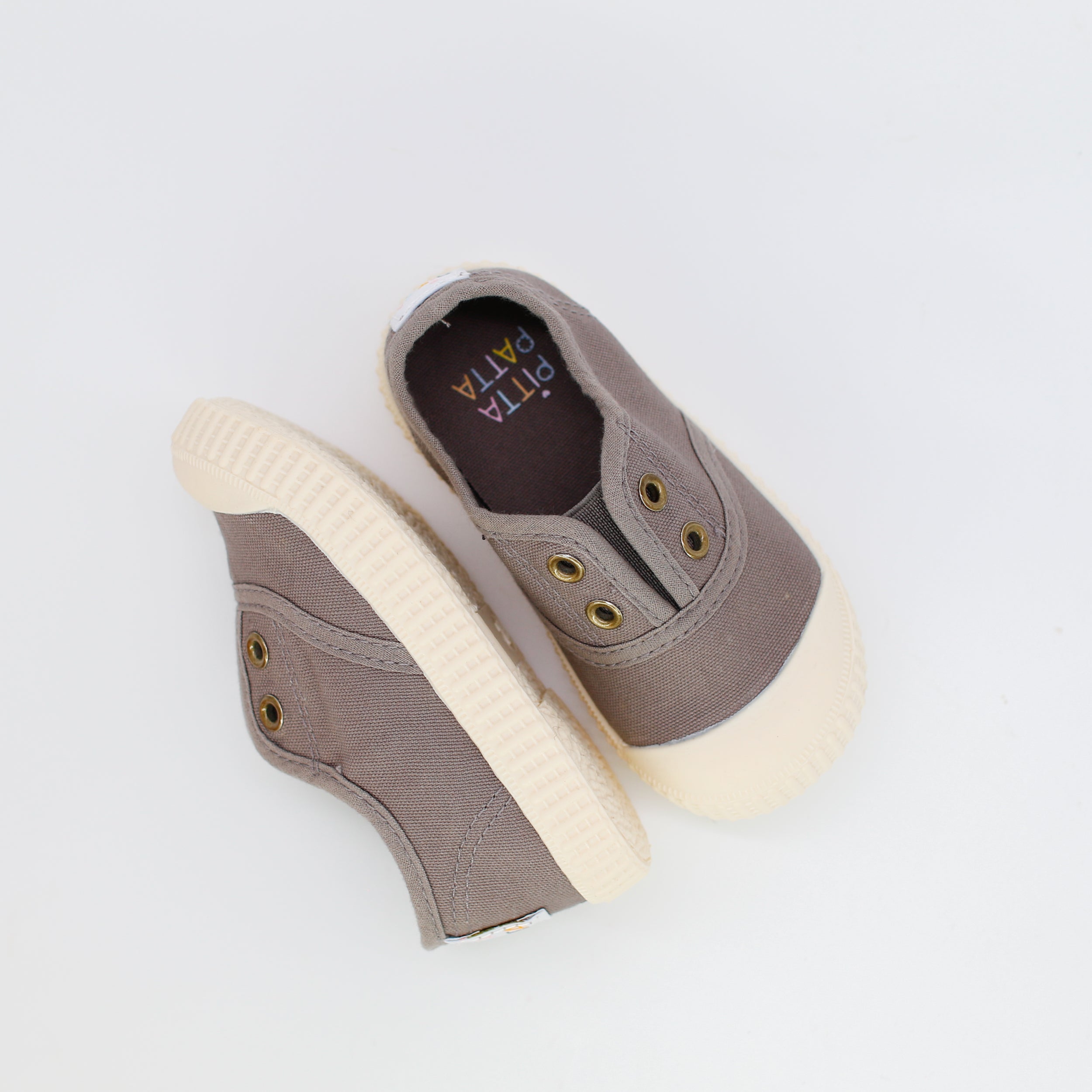 Pair of brown children's shoes with white soles on a light gray background