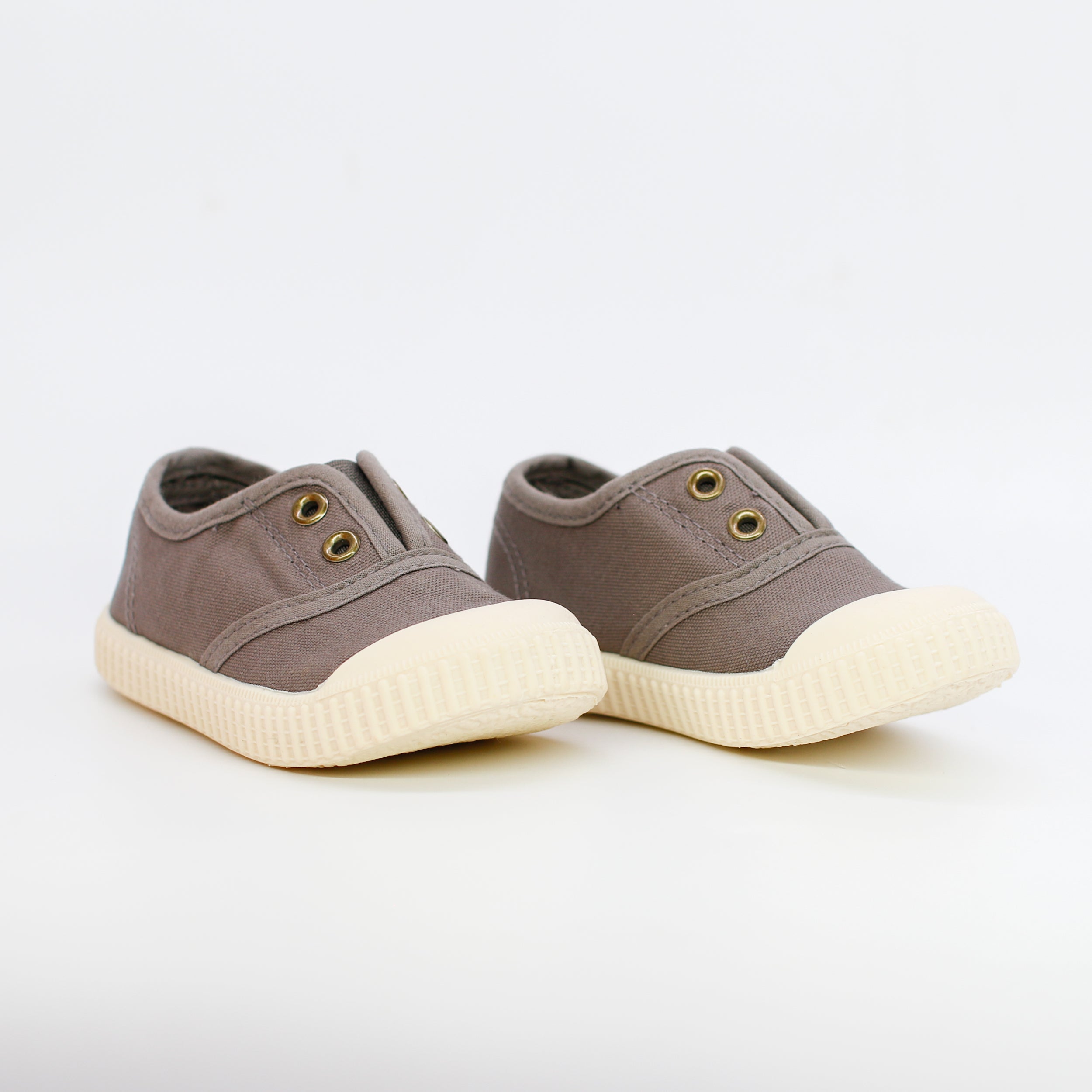 Pair of brown children's shoes with white soles on a light gray background