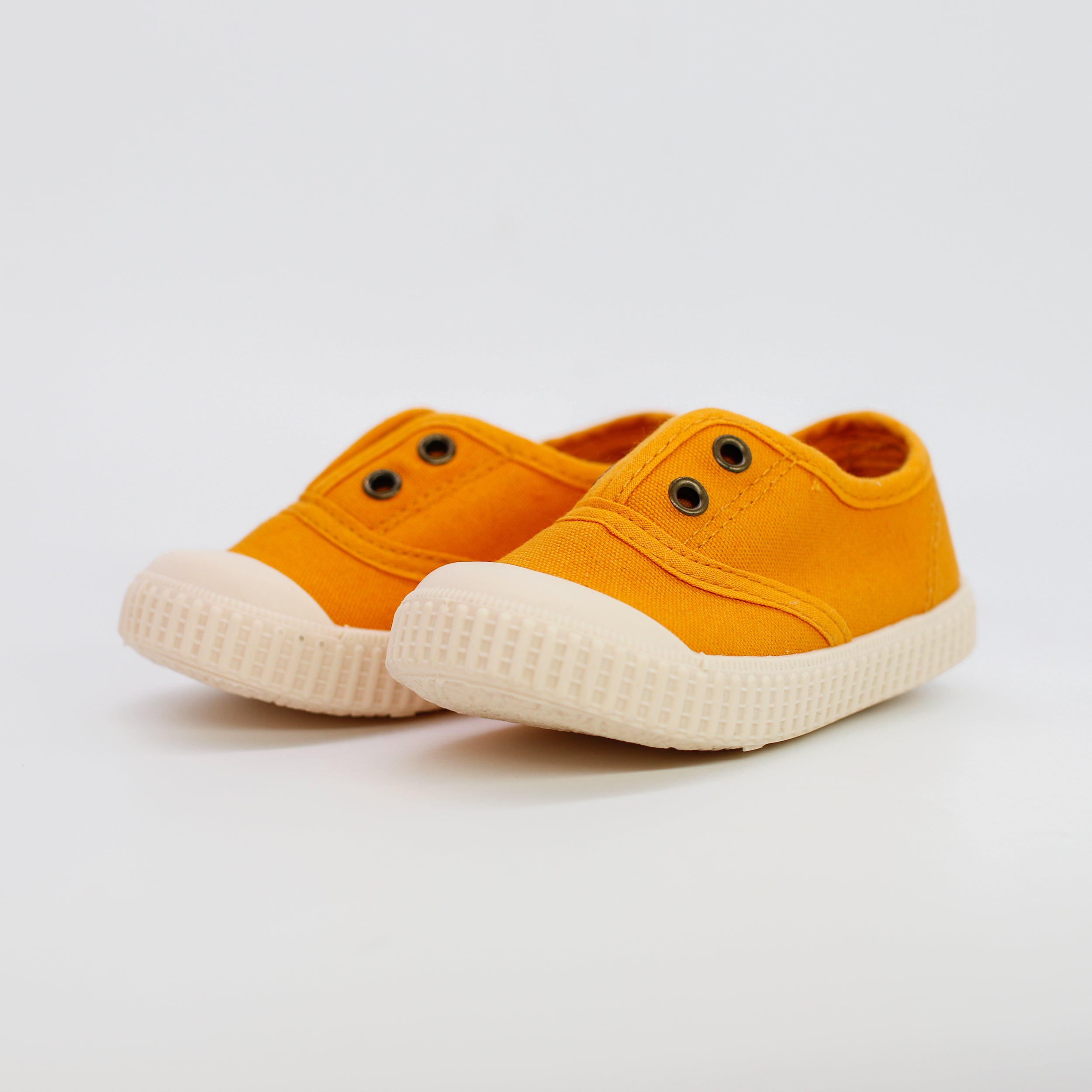 Pair of orange sneakers with white soles on a light gray background