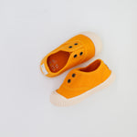 Pair of orange children's shoes on a light gray background