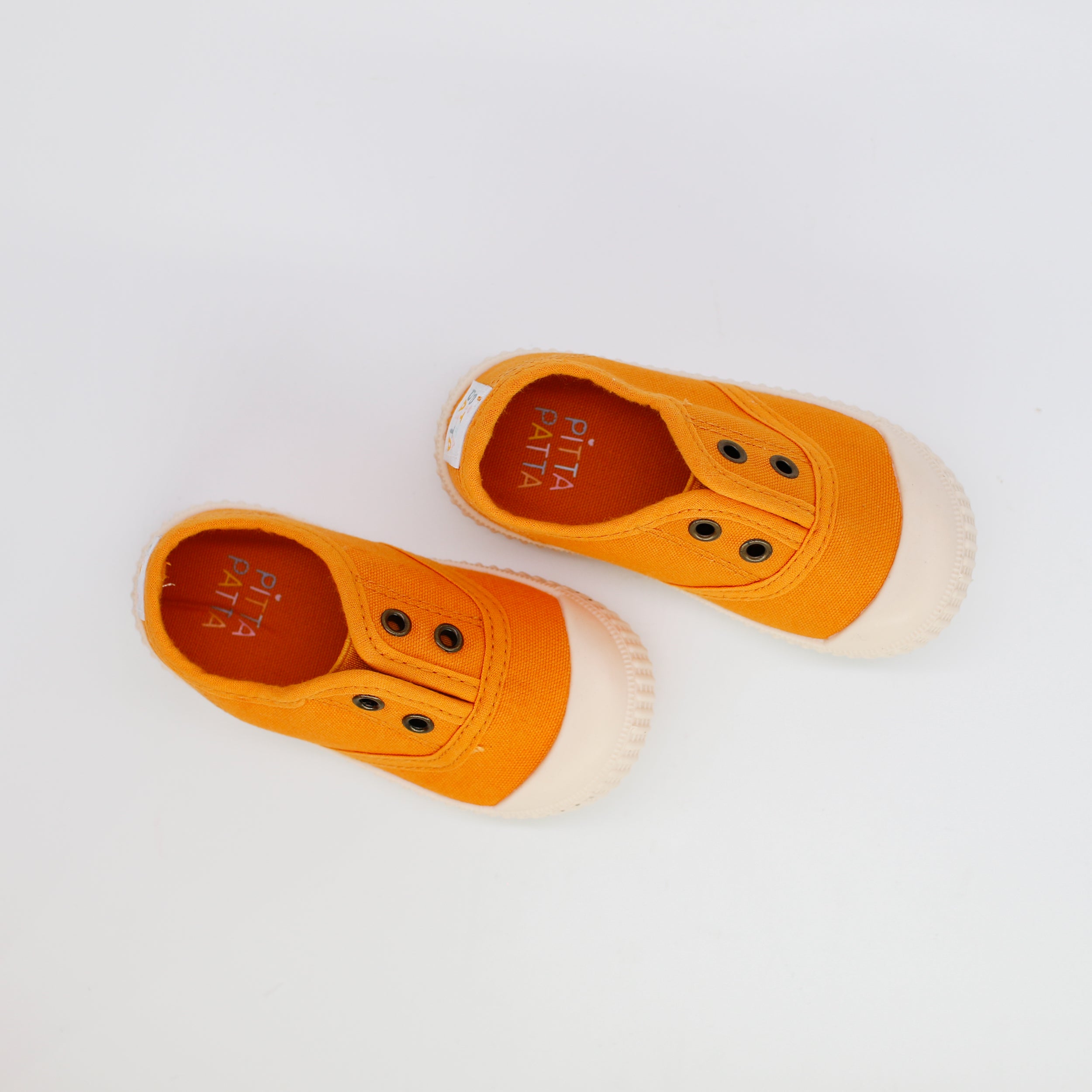 Pair of orange children's shoes with white soles on a light gray background
