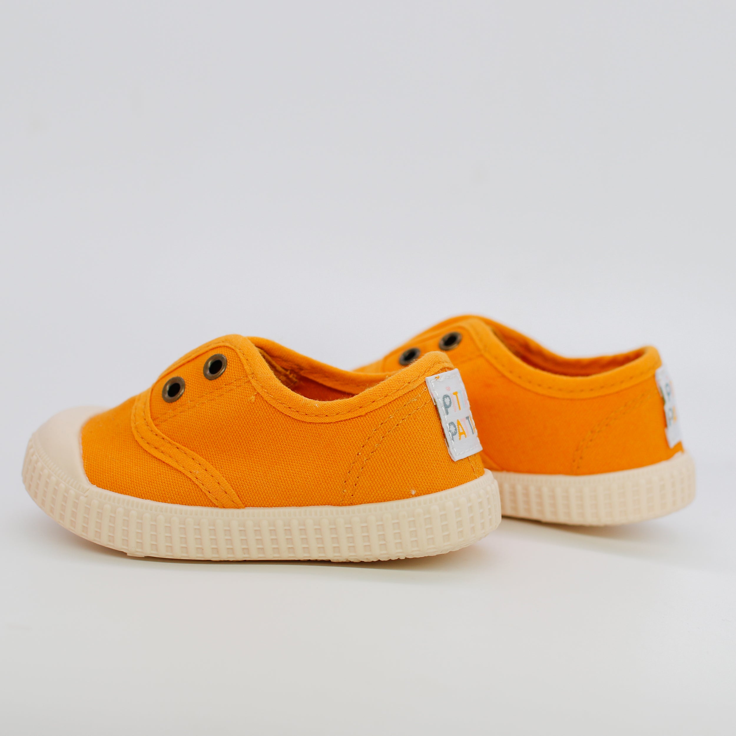 Orange children's sneakers with white soles on a light gray background