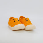 Pair of orange sneakers with white soles on a light gray background