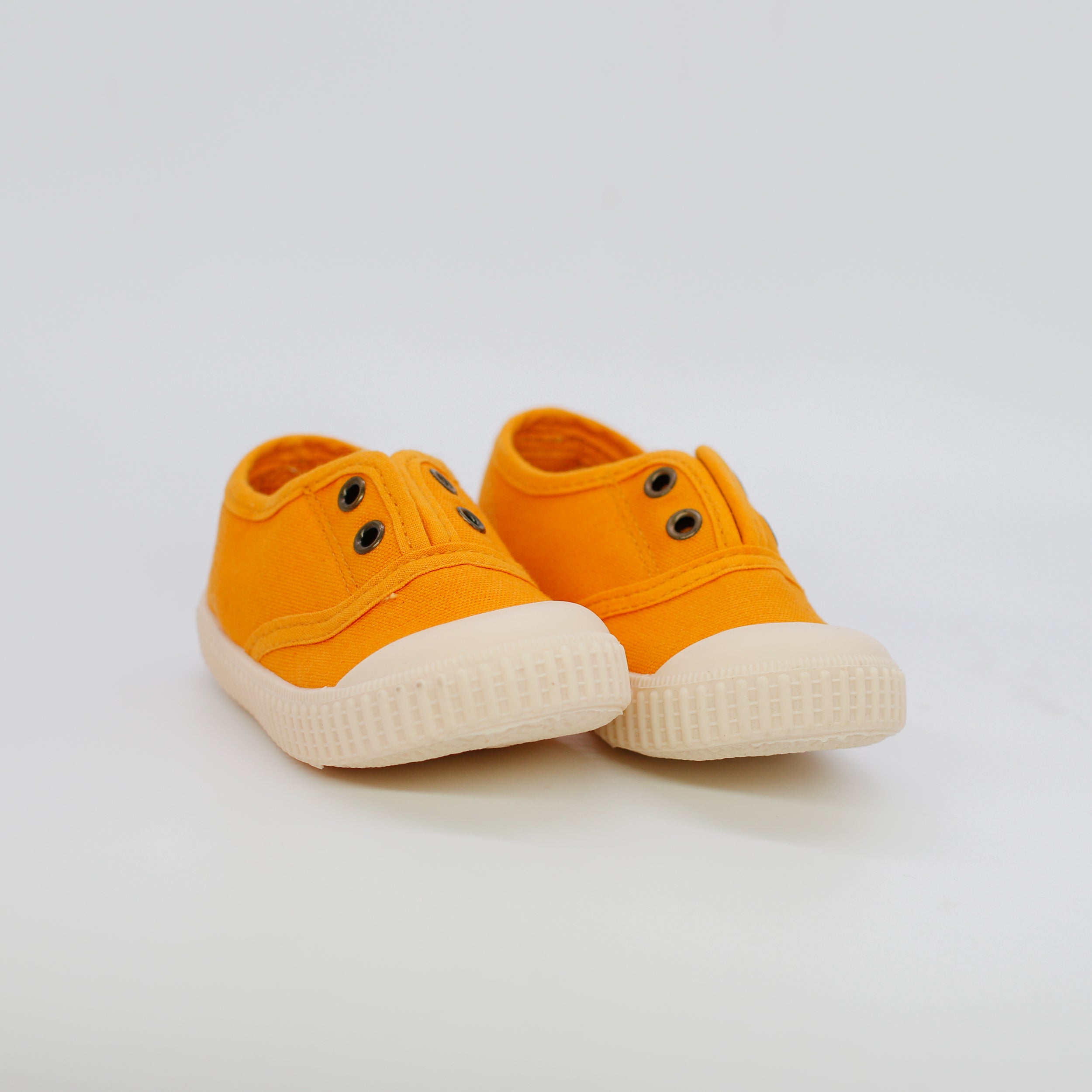 Pair of orange sneakers with white soles on a light gray background
