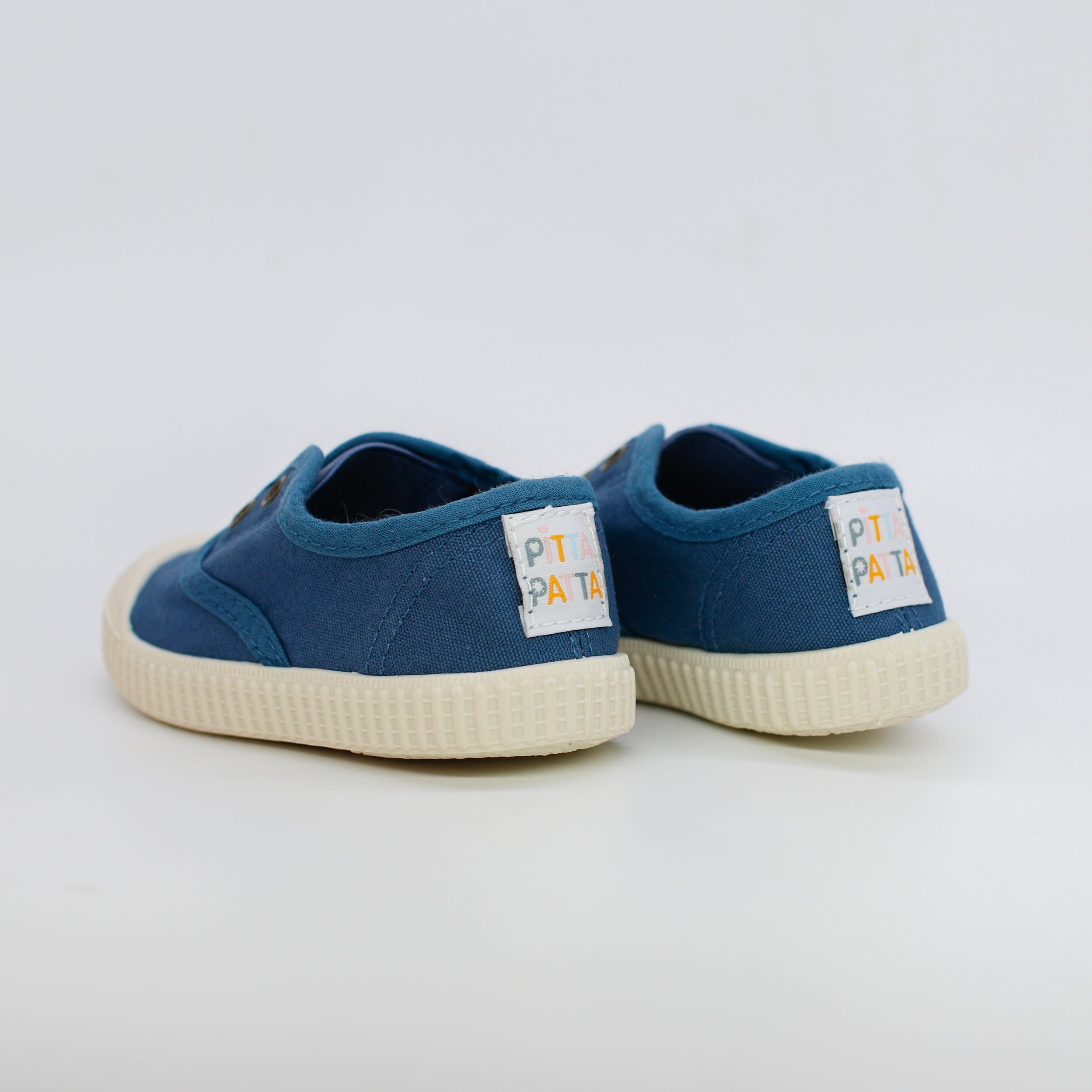Pair of blue children's shoes with white soles on a light gray background