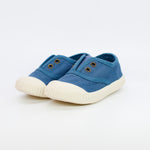 Pair of blue children's sneakers with white soles on a light gray background