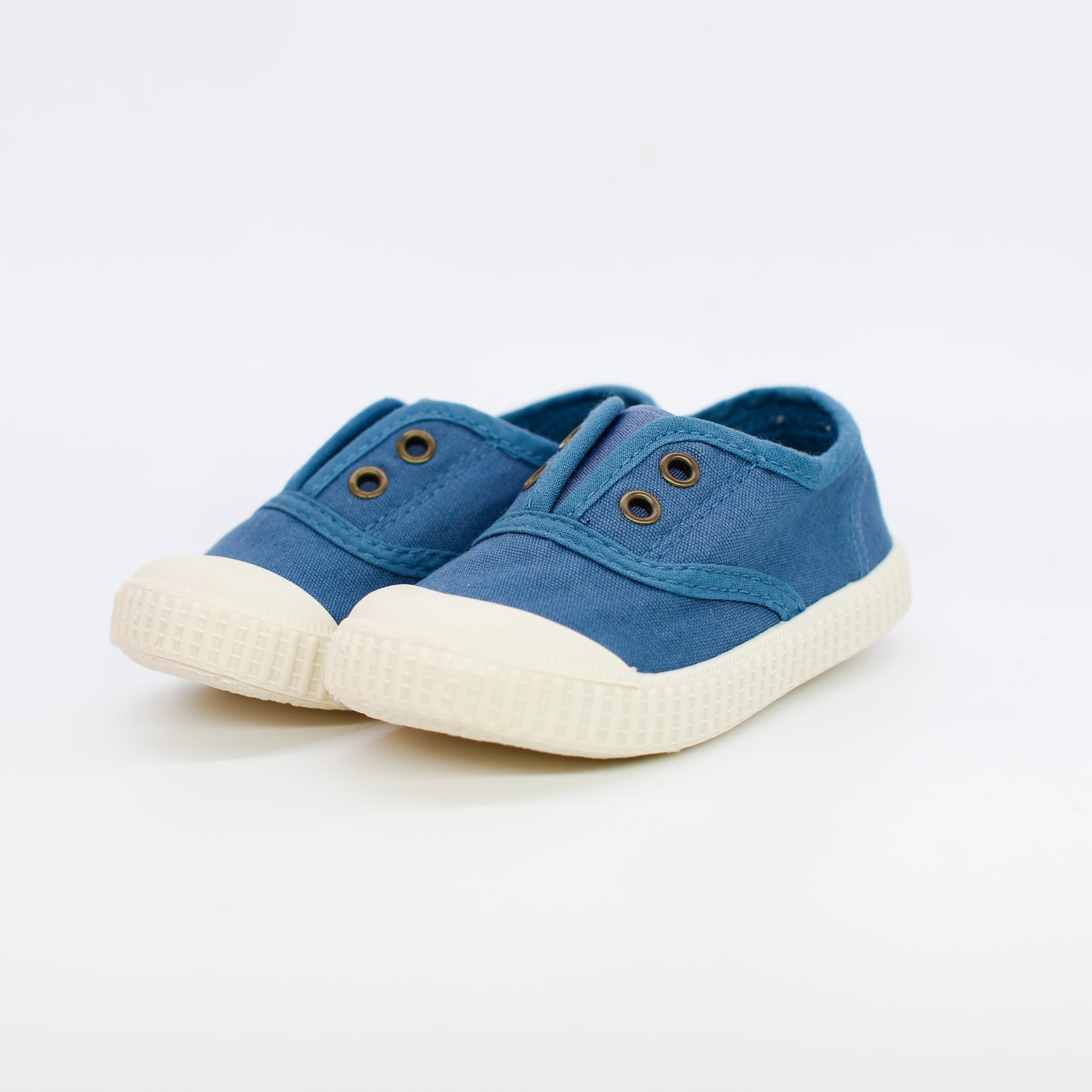Pair of blue children's sneakers with white soles on a light gray background