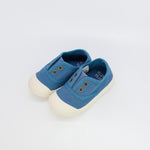 Pair of blue children's shoes with white soles on a light gray background