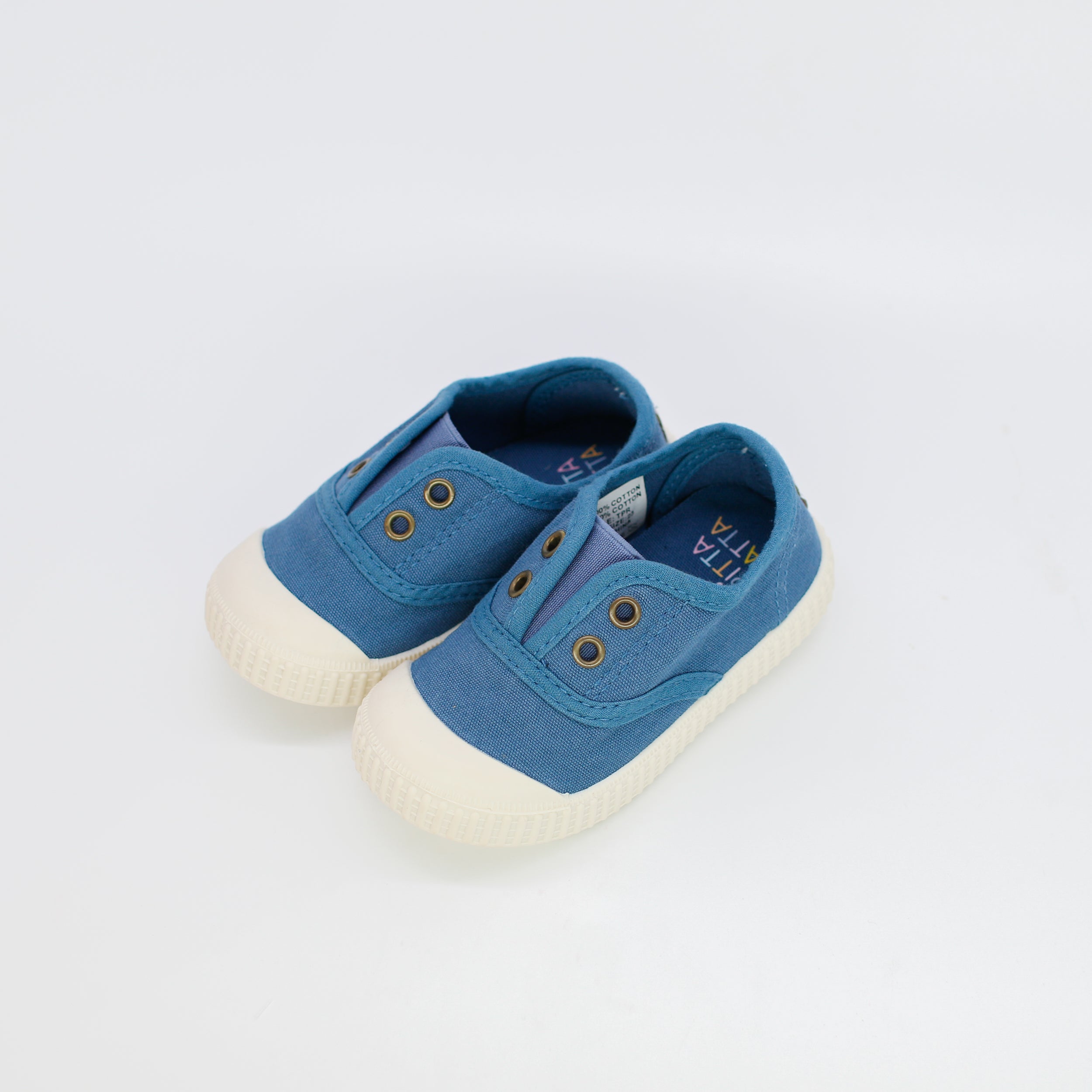 Pair of blue children's shoes with white soles on a light gray background