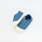 Blue baby shoes with white soles on a light gray background
