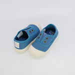 Pair of blue children's shoes with white soles on a light gray background