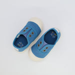 Pair of blue children's shoes with white soles on a light gray background